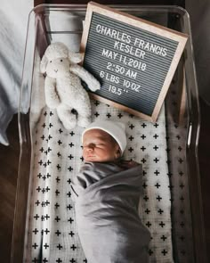 a baby in a crib with a teddy bear and a sign that says charles franks