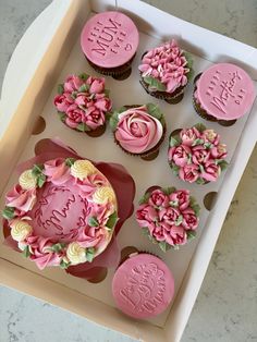 cupcakes with pink frosting and flowers in a box