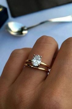 a woman's hand with two gold rings and a diamond ring on her finger