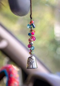 a bell hanging from the side of a car with colorful beads and bells attached to it