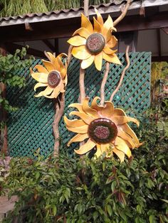 three metal sunflowers on display in a garden