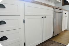 a kitchen with white cabinets and black knobs