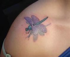 a dragonfly tattoo on the back of a woman's left side belly,