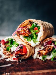 chicken wrap with lettuce and tomato on wooden cutting board