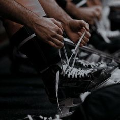 two people tying up their shoes with white laces on the bottom and one person wearing black sneakers