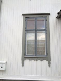 a cat sitting on the ledge of a window sill in front of a white building