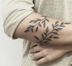 a woman's arm with leaves on it and the word love written in black ink