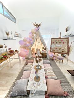 a room filled with lots of pillows and balloons on the floor next to a teepee tent