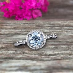 an engagement ring with a blue topaz surrounded by white diamonds on a wooden surface