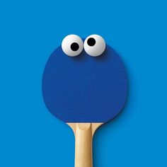 a ping pong paddle with two eyes on it's side, against a blue background