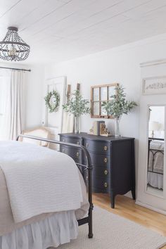 a bedroom with a bed, dresser and mirror on the wall next to a window