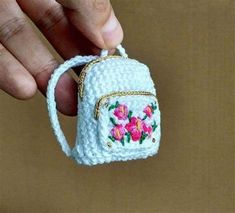 a small crocheted purse being held by someone