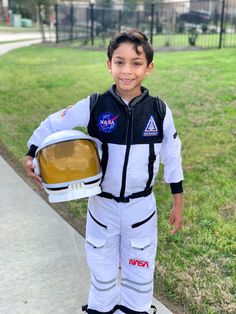 a young boy in an astronaut suit holding a helmet