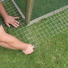 a person standing next to a fence with their foot on the ground and one hand reaching for something