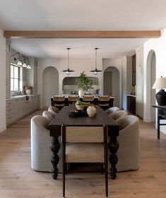 a dining room table surrounded by chairs in front of an open kitchen and living room