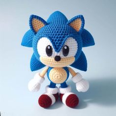 a crocheted sonic doll is posed on a blue background