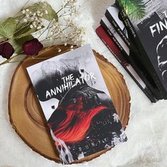 the annihilator book sitting on top of a wooden slice next to some flowers