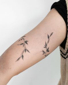 a woman with a tattoo on her arm that has small flowers growing out of it