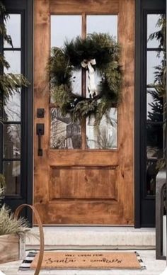 the front door is decorated with wreaths and greenery for christmas time as well