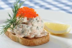 a piece of bread with crab salad on it next to a lemon and dill garnish