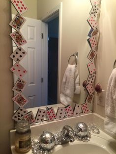 a bathroom mirror with playing cards hanging from it's sides in front of a sink