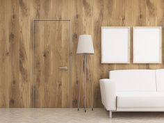 a white couch sitting next to a lamp on top of a hard wood floor in front of a wooden wall