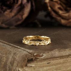 a gold wedding band sitting on top of a wooden table next to an old book