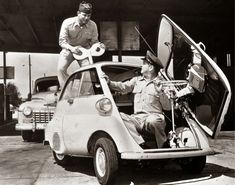 two men are sitting in the back of a small car