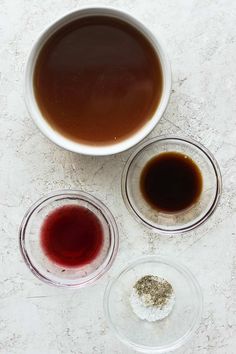 three bowls filled with different types of liquid and seasoning on top of a table