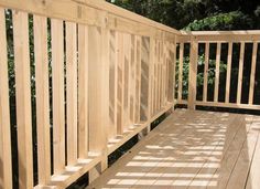 a wooden deck with railing and trees in the background