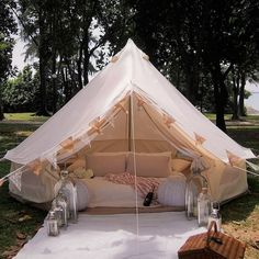 a tent set up in the grass with pillows and blankets