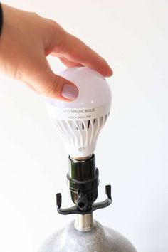 a person is holding an electric bulb on top of a metal object with one hand