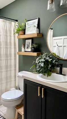 a white toilet sitting next to a sink in a bathroom under a mirror and potted plant