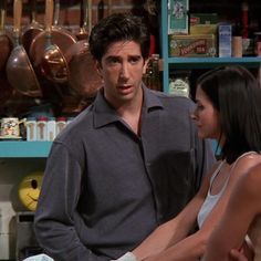 the young man and woman are standing together in front of shelves with cooking utensils