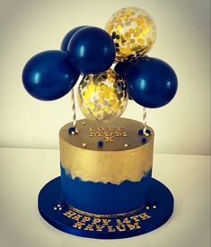 a blue and gold birthday cake with balloons on top