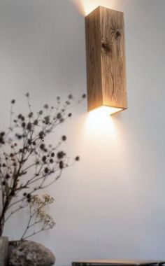 a light that is on the side of a wall next to a vase with flowers