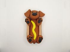 a cookie shaped like a hot dog on a white surface with black feet and yellow tail