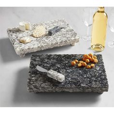 two wine glasses, cheese and crackers on a marble serving tray with corks