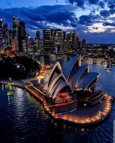 an aerial view of the sydney opera house at night, with city lights in the background