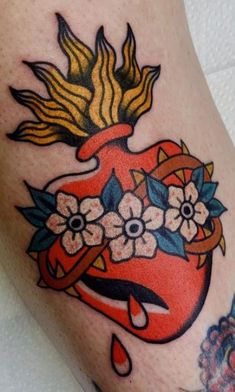 an old school style tattoo with flowers and a heart on the side of someone's leg