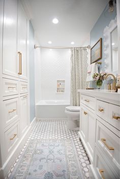 a white bathroom with blue walls and gold trim on the shower curtain, toilet and bathtub