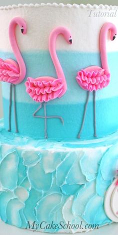 two pink flamingos on top of a blue and white cake