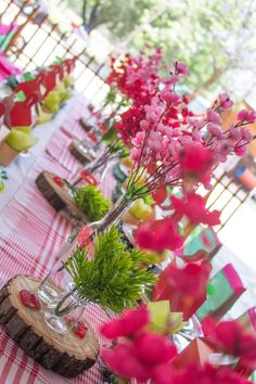 there are many vases with flowers in them on the table at this outdoor party