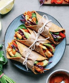 a plate topped with cut in half sandwiches next to a cup of tea and cilantro