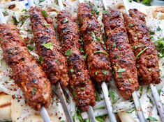 several skewered meats are being cooked on a grill with onions and parsley