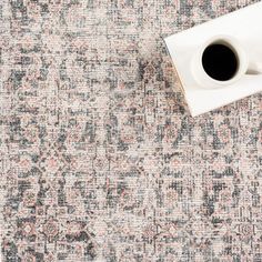 a cup of coffee sits on top of an old, worn rug with faded edges