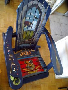 a blue rocking chair with pictures painted on the back and sides, sitting in a kitchen