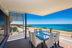 a dining room table with white chairs next to an ocean view