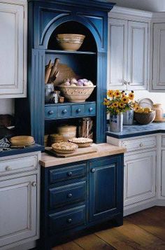 an image of a kitchen setting with blue cabinets and white cupboards on the left side