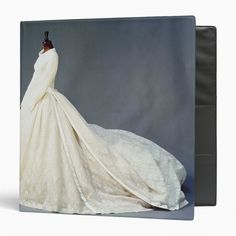 a white wedding dress on display in front of a gray background